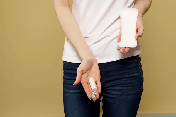 Lány egy tampon és egy pad a kezében egy bézs háttér vágott kilátás a menstruáció kritikus napok — Stock Fotó