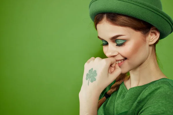 Buena chica con un trébol en la mano en un fondo verde vacaciones St. Patricks día divertido sombrero en su cabeza — Foto de Stock