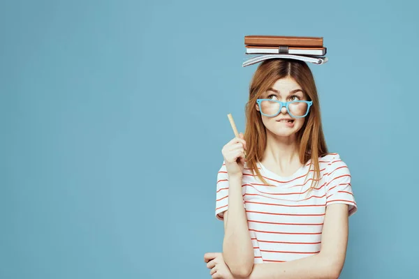 Étudiante avec des livres sur sa tête science éducation fond bleu émotions geste avec les mains — Photo