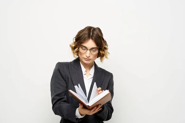 Жінка на роботі з книгою на світлому фоні класичний костюм окуляри голова — стокове фото
