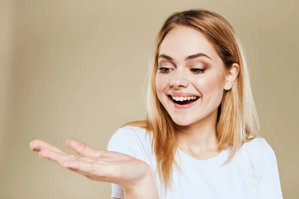 Mulher alegre em um branco gestos camiseta com as mãos emoções bege fundo — Fotografia de Stock