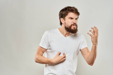 Sakallı bir adam elleri beyaz tişörtlü agresiflik arka planında hareket ediyor.