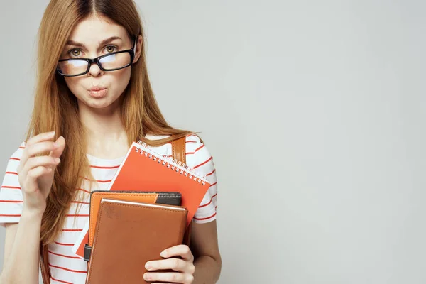 Vrouwelijke student met notitieblok en bril op een lichte achtergrond bijgesneden weergave van een gestreept T-shirt — Stockfoto