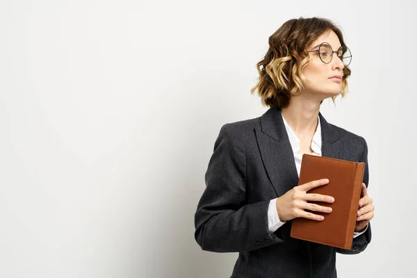 Femme d'affaires dans un costume avec des documents dans les mains fond clair coiffure bouclée — Photo
