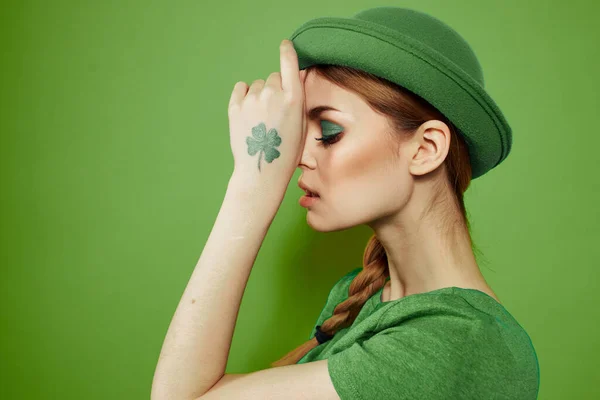 Buena chica con un trébol en la mano en un fondo verde vacaciones St. Patricks día divertido sombrero en su cabeza — Foto de Stock