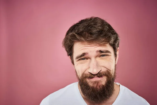 Barbudo hombre en blanco camiseta emociones disgustado facial expresión estudio rosa fondo —  Fotos de Stock