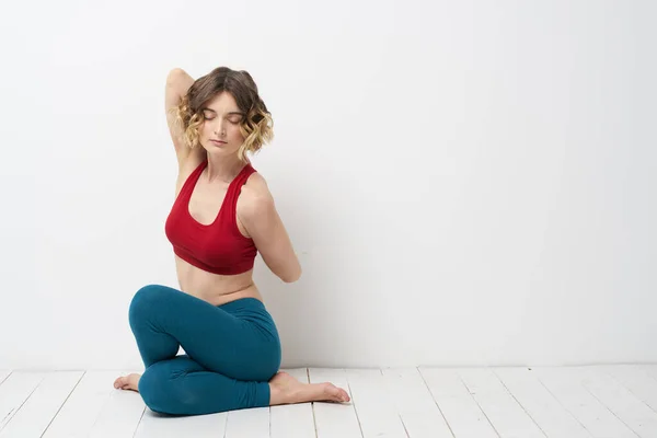 Kvinna gör yoga full längd inomhus blå leggings röd tank top — Stockfoto