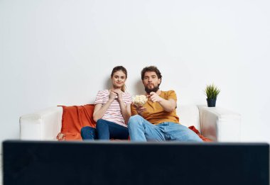 Bir adam ve bir kadın kanepede televizyon seyrediyor.