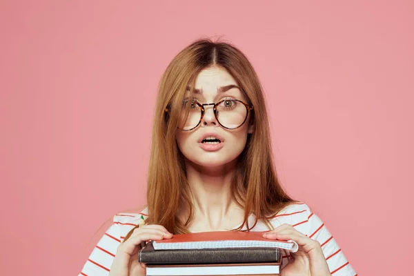 Joven estudiante con libros sobre gafas de fondo rosa en el instituto de educación facial vista recortada —  Fotos de Stock