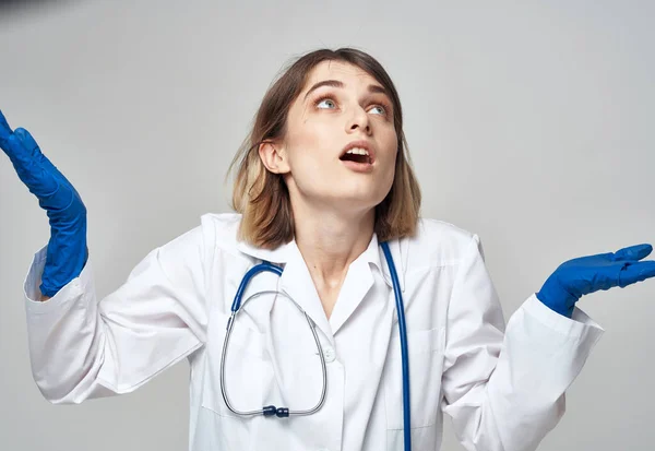 Emotional woman in blue medical gloves touches her head with her hands — Stock Photo, Image
