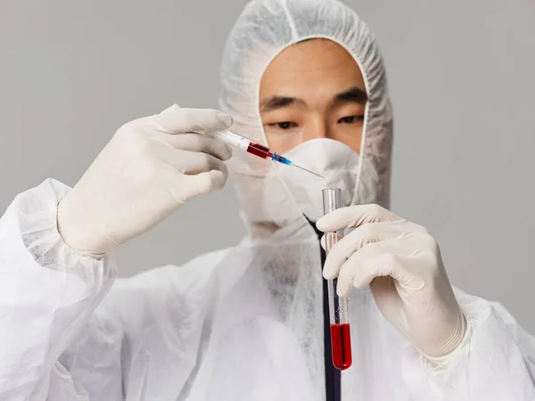 Male laboratory assistant protective mask syringe in the hands of research diagnostics