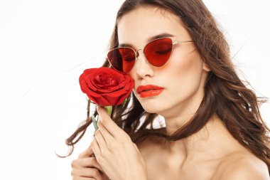 Kırmızı gül ve güneş gözlüklü, çıplak omuzlu esmer kız.