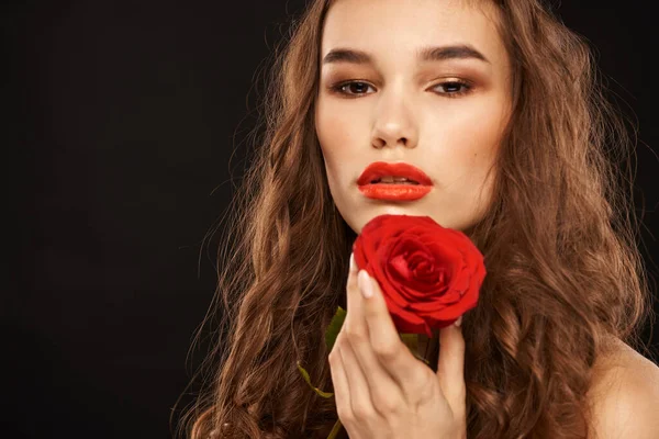 Femme avec une rose rouge sur un fond sombre cheveux longs maquillage lèvres rouges — Photo