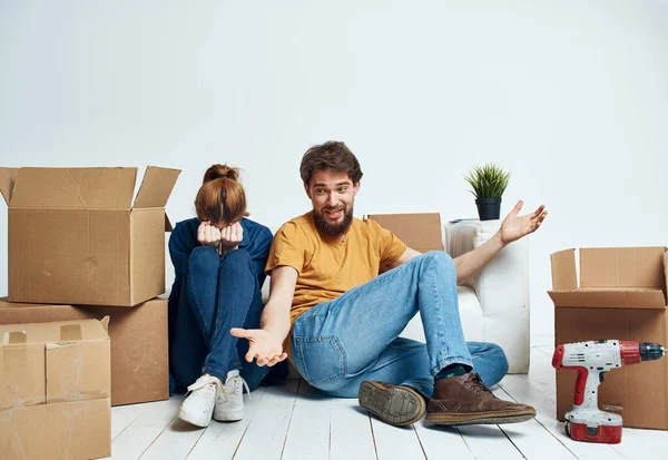 Hombre y mujer en los pisos en un nuevo apartamento con cajas y herramientas para la reparación — Foto de Stock