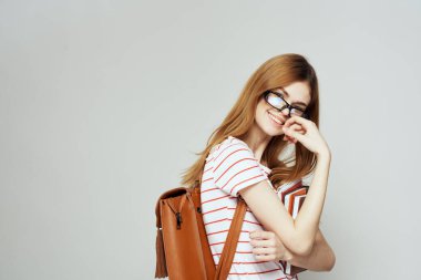 Hafif arka planda not defteri ve gözlüklü bayan öğrenci çizgili bir tişörtü kırpmış.