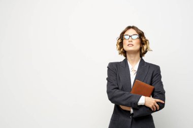 Not defteri ve gözlüklü bir iş kadını takım elbise modelinin hafif arka planında çalışıyor..