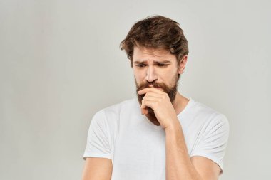 Beyaz tişörtlü, sakallı, duyguları sakallı bir adam yüz ifadesinden memnun değildi.