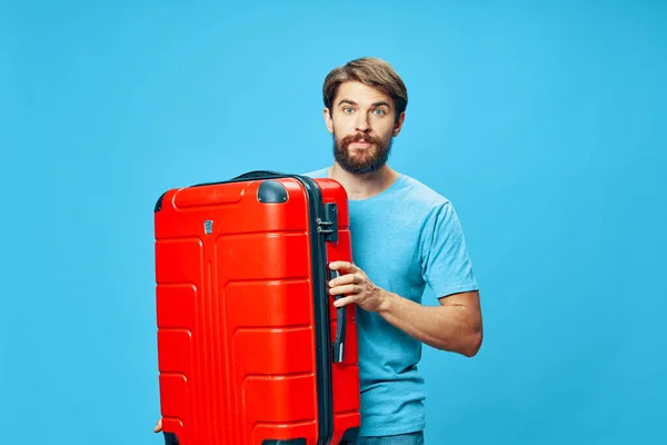 Viajero con una maleta roja camiseta azul bigote de fondo aislado —  Fotos de Stock