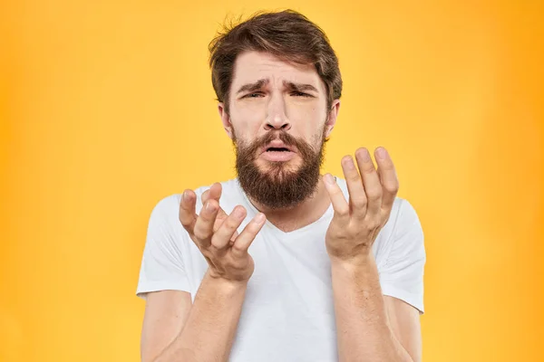 Een man in een wit t-shirt gebaart met zijn handen studio levensstijl gele achtergrond emoties — Stockfoto