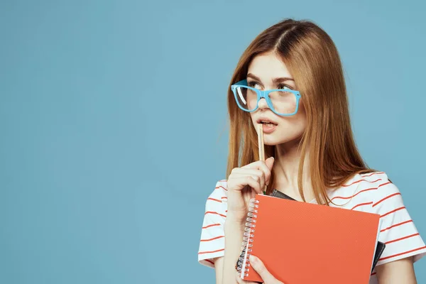 Ragazza in occhiali alla moda con quaderni in mano su uno sfondo blu vista ritagliata Copia spazio — Foto Stock