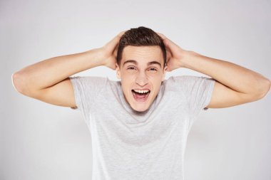 Beyaz tişörtlü bir adam elleri yakın kırpılmış arka planda hareket eder.