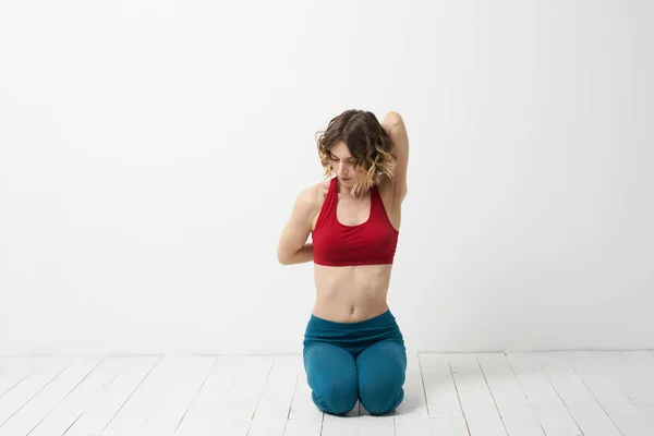 Flickan är engagerad i yoga på en ljus bakgrund Röd T-shirt gestikulera med händerna — Stockfoto