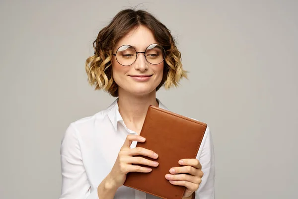 Femme avec bloc-notes dans les mains travail d'affaires beige fond lunettes coiffure — Photo