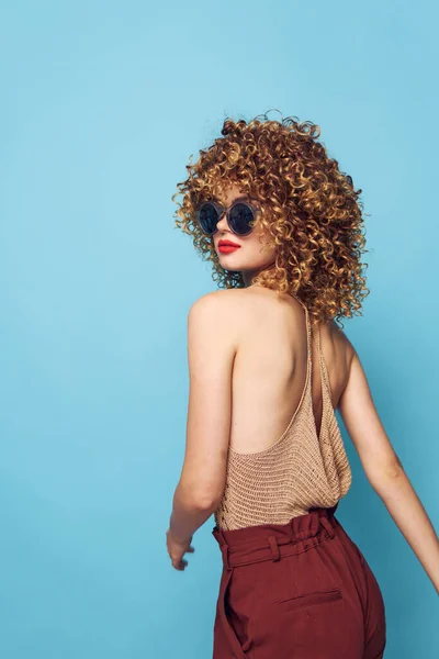 Mooie vrouw mode levensstijl donker zonnebril blauw achtergrond krullend haar — Stockfoto