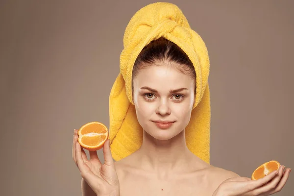 Mulher com laranjas nas mãos emoções ombros nus toalha na cabeça bege fundo — Fotografia de Stock