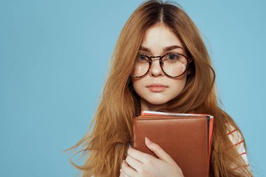 Notları ve mavi gözlükleri olan enerjik bir bayan öğrenci.