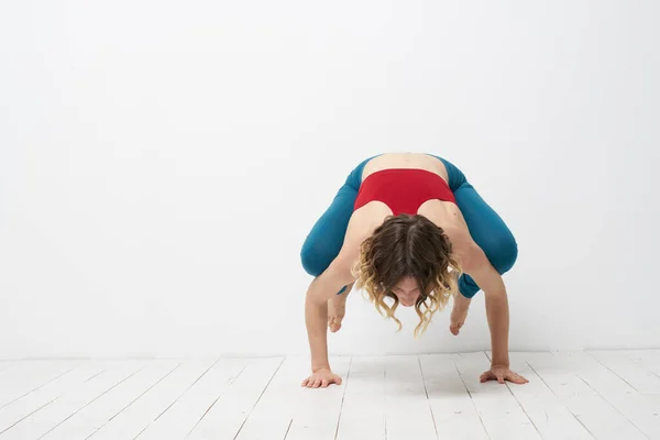 Wanita melakukan yoga full length indoors blue leggings red tank top — Stok Foto
