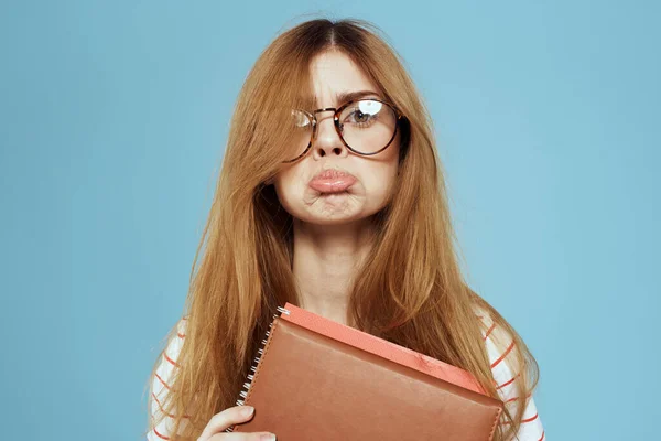 Estudante feminino enérgico com blocos de notas e óculos modelo fundo azul — Fotografia de Stock