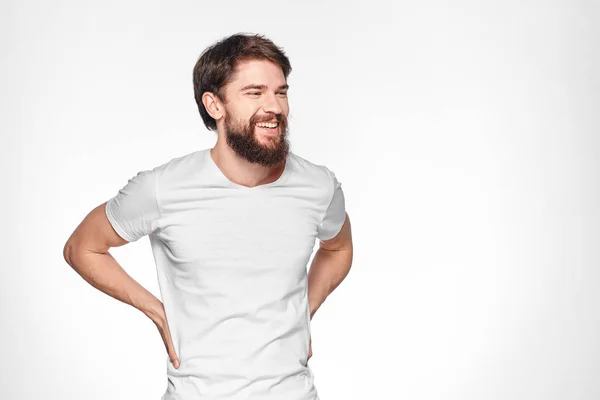 Homem barbudo em gesto t-shirt branco com as mãos emoções luz fundo — Fotografia de Stock