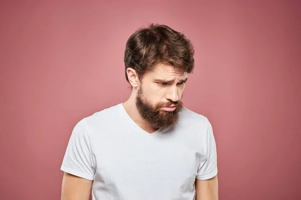 Emotionell man vit t shirt ledsen ansiktsuttryck rosa bakgrund — Stockfoto