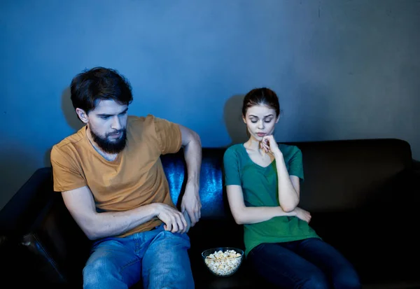 frightened woman and man watching a movie in the evening in front of tv on the couch