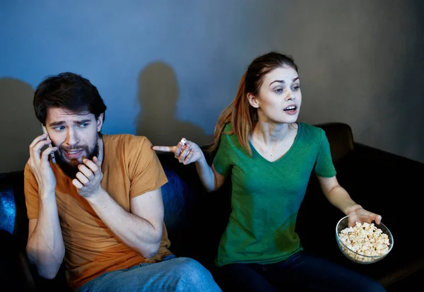 Männer und Frauen auf der Couch In einem dunklen Raum, der einen Horrorfilm anschaut — Stockfoto