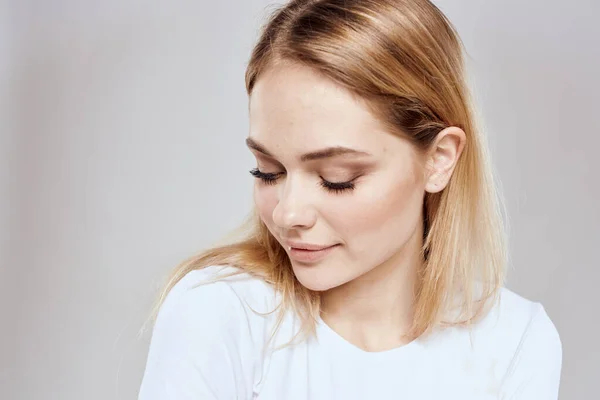 Блестящая блондинка в белой футболке обрезанный вид светлый фон — стоковое фото