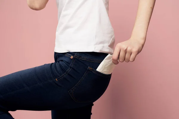 Mujer con almohadilla cerca de jeans y agente protector de higiene para el ciclo menstrual — Foto de Stock