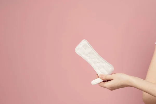 Védőpárna és tampon női kezekben egy rózsaszín háttér menstruáció kritikus nap — Stock Fotó