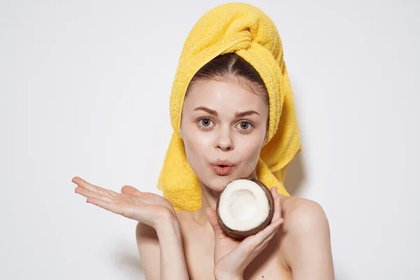 Glad kvinna bakom ett djur med en handduk på huvudet med en kokos i händerna exotiska frukter naturliga kosmetika — Stockfoto