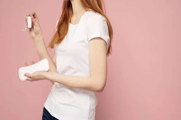 Donna con un pad in mano su uno sfondo rosa jeans T-shirt assorbenti igienici frequenza — Foto Stock