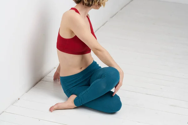 Kvinna gör yoga full längd inomhus blå leggings röd tank top — Stockfoto