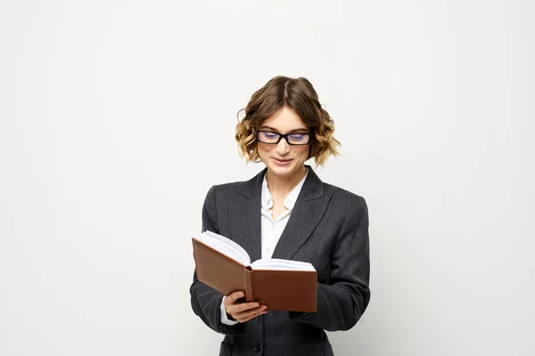 Not defteri ve gözlüklü bir iş kadını takım elbise modelinin hafif arka planında çalışıyor.. — Stok fotoğraf