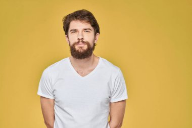 Duyguları olan sakallı adam beyaz tişört, eğlenceli yaşam tarzı, sarı arka plan.