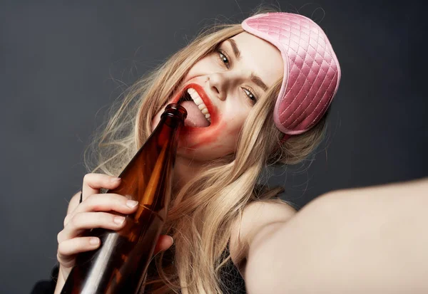 Chica rubia borracha con una botella de gestos de cerveza con sus manos y un modelo de adicción al maquillaje brillante — Foto de Stock