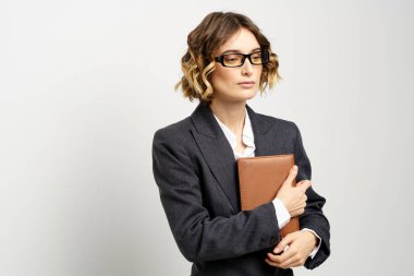 Klasik takım elbiseli bir iş kadını elinde bir not defteri ve yüzünde gözlüklerle.