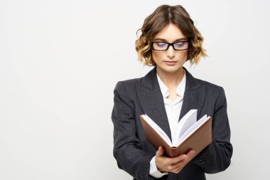Klasik takım elbiseli bir iş kadını elinde bir not defteri ve yüzünde gözlüklerle.