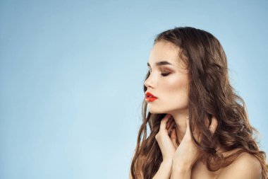 Güzel bir kadın. Çıplak omuzlar. Saç bakım, parlak makyaj, mavi arka plan.