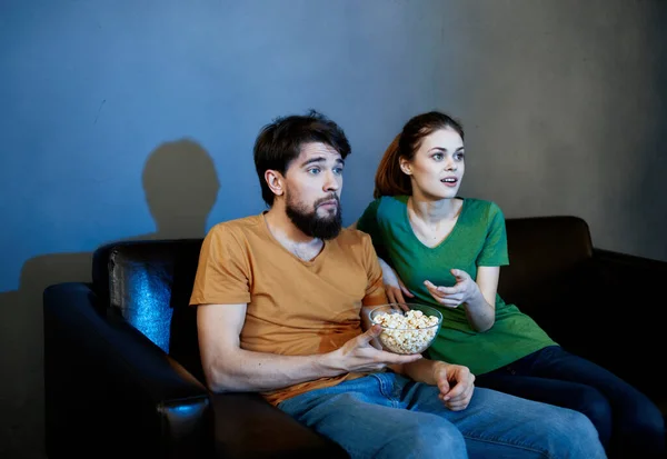 Schöner Mann und junge Frau auf Sofa drinnen vor dem Fernseher am Abend — Stockfoto