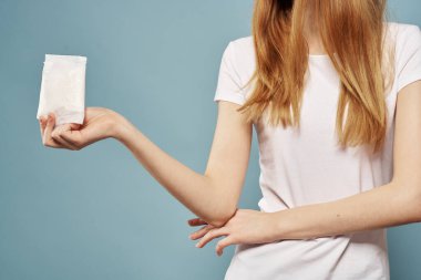 Mavi arka planda yastıklı bir kız. Adet günleri, hijyenik görünüm.